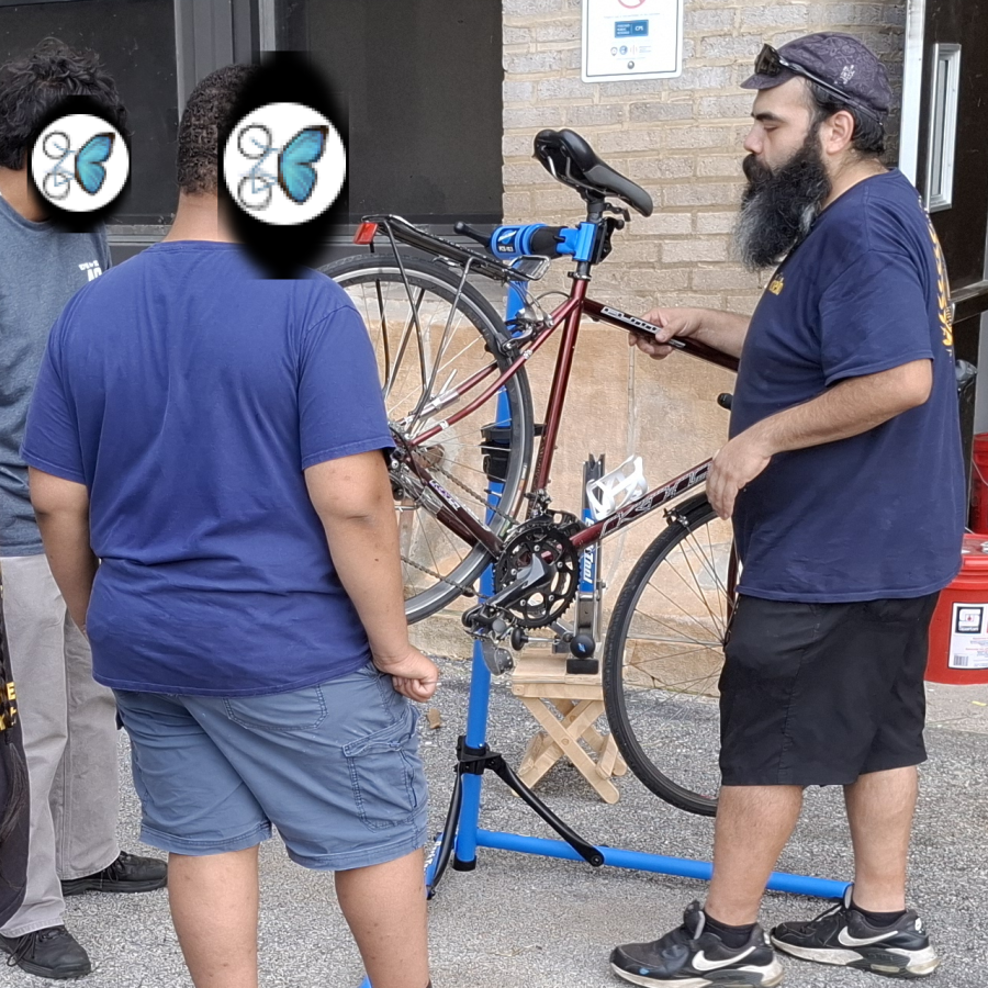 A volunteer and a neighbour working on a bike together at a repair stand